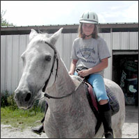 Young girl riding a white horse